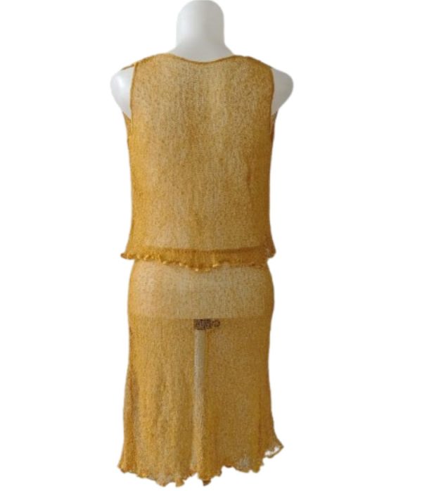 Setelan rajut transparan (sheer) singlet crop top dan mini skirt kuning emas, dilihat dari belakang.